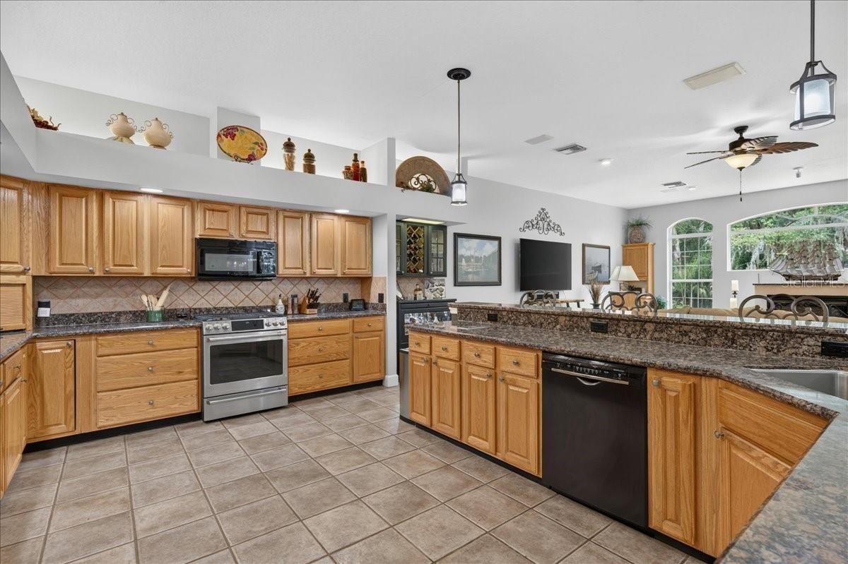 The spacious, well-appointed kitchen features abundant oak cabinetry, granite countertops, stainless steel appliances, a gas range, wine storage and an elevated breakfast bar with seating overlooking and flowing seamlessly into the family room and breakfast nook.