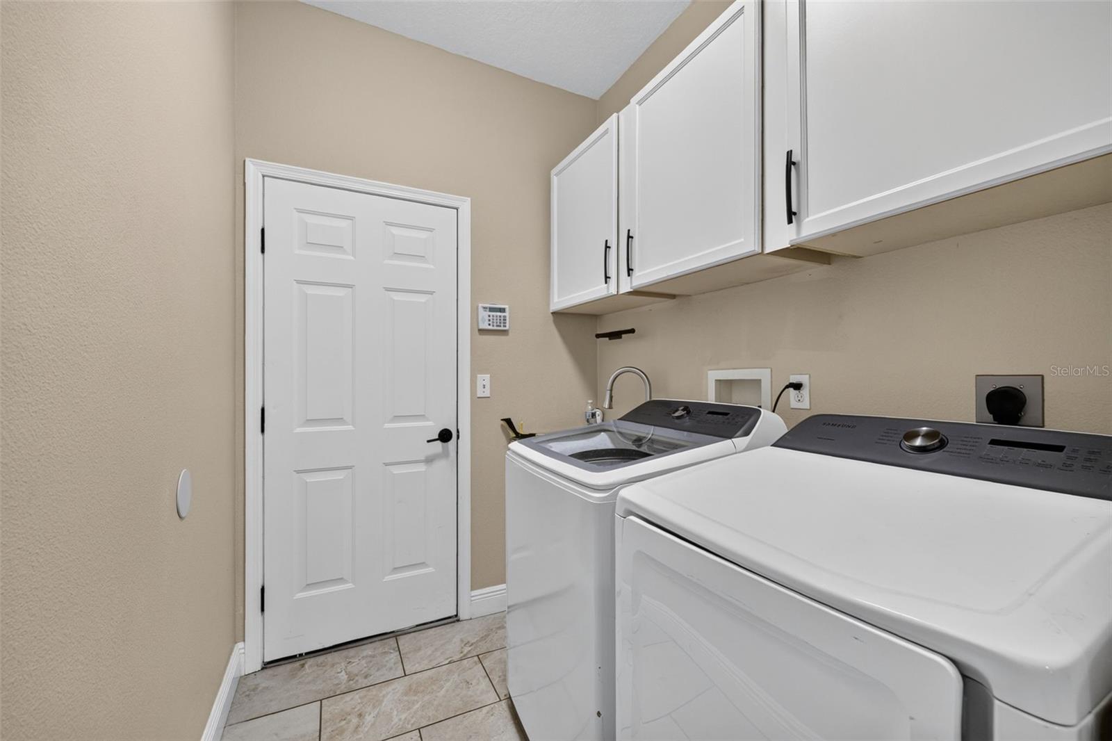 Laundry area with built in cabinets, laundry tub and leads into the 3 car garage
