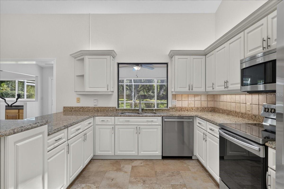 The light and bright eat-in kitchen feels both polished and welcoming, with rich wood cabinetry, granite countertops, stainless steel appliances and generous workspace for everyday meals and entertaining.