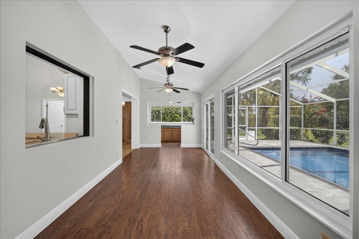 A pass-through connects the kitchen to the spacious Florida room, where walls of windows and impact sliding doors bring in views of the pool and expansive backyard.