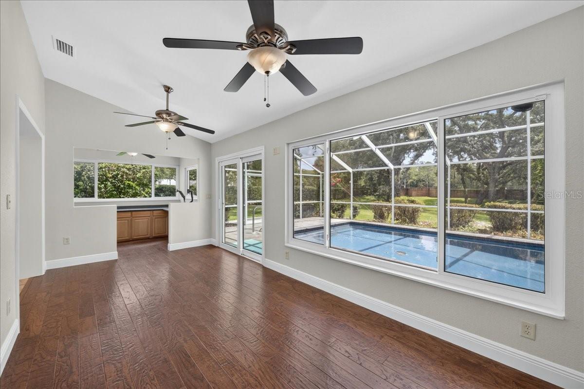 A pass-through connects the kitchen to the spacious Florida room, where walls of windows and impact sliding doors bring in views of the pool and expansive backyard.