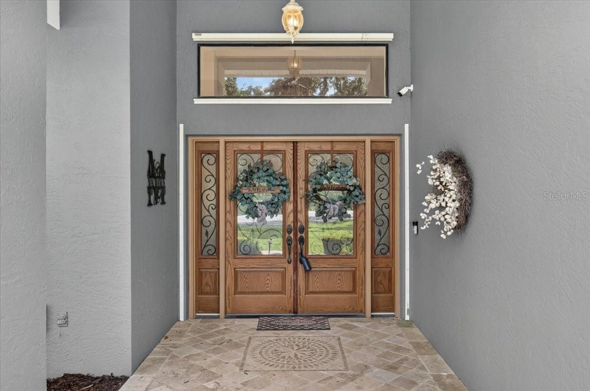Welcoming covered entry with double-glass wrought iron front doors with sidelights and transom window.