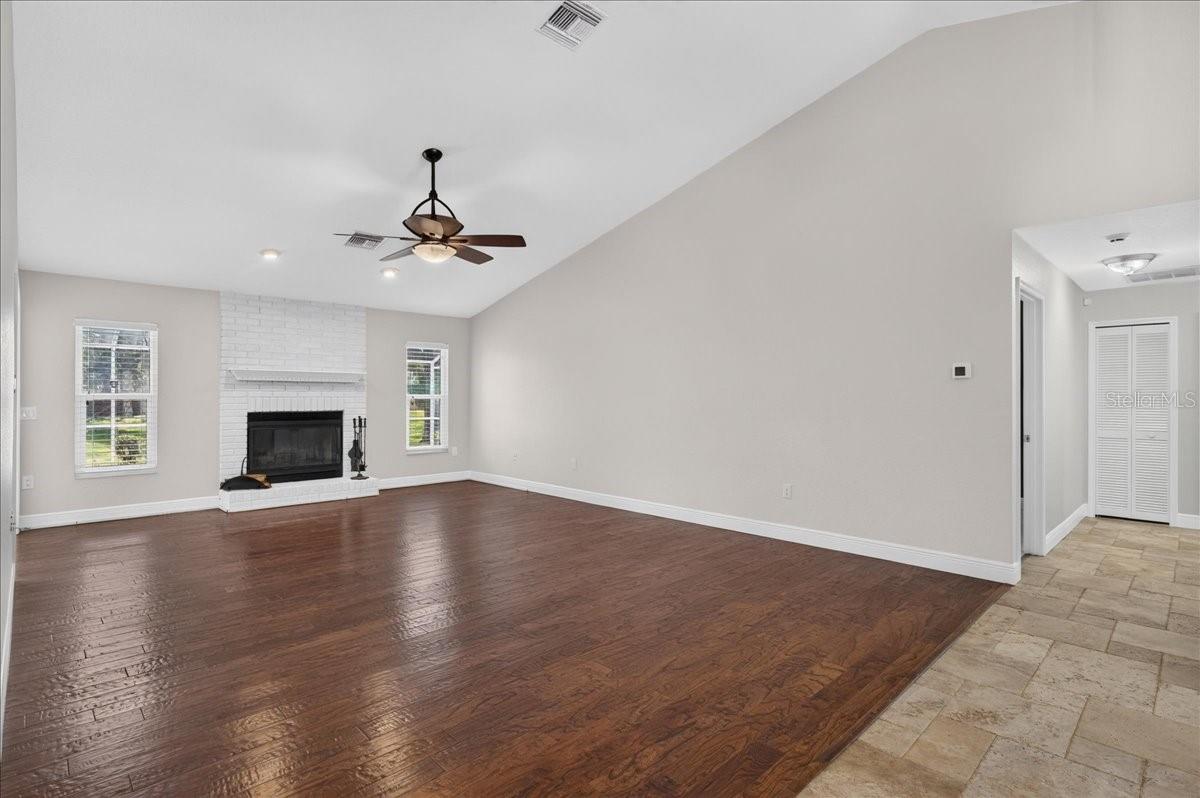 Vaulted ceilings and engineered hardwood floors enhance the main living area, where a whitewashed brick wood-burning fireplace and mantel add warmth and character.