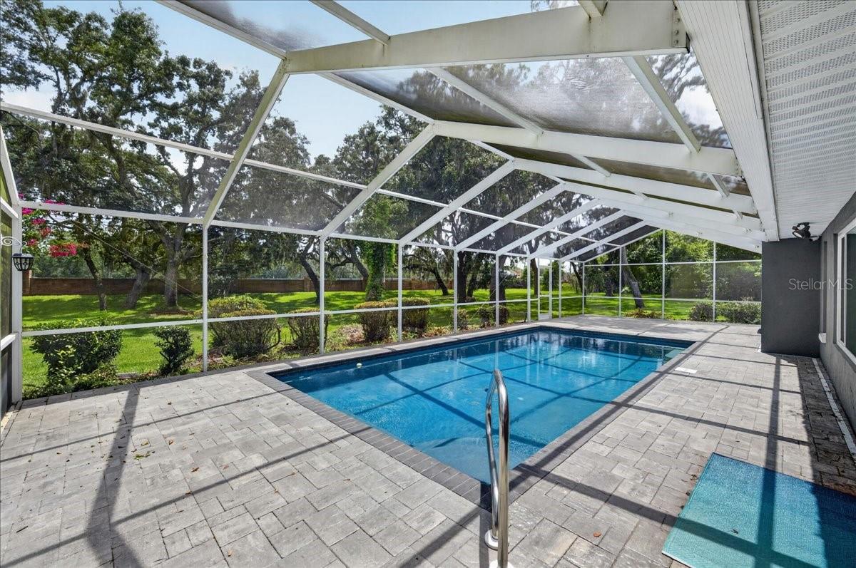 Step out to the screened-in saltwater pool and surrounding travertine patio, where the expansive backyard, lush greenery and mature trees create a natural backdrop for swimming, dining and relaxing.