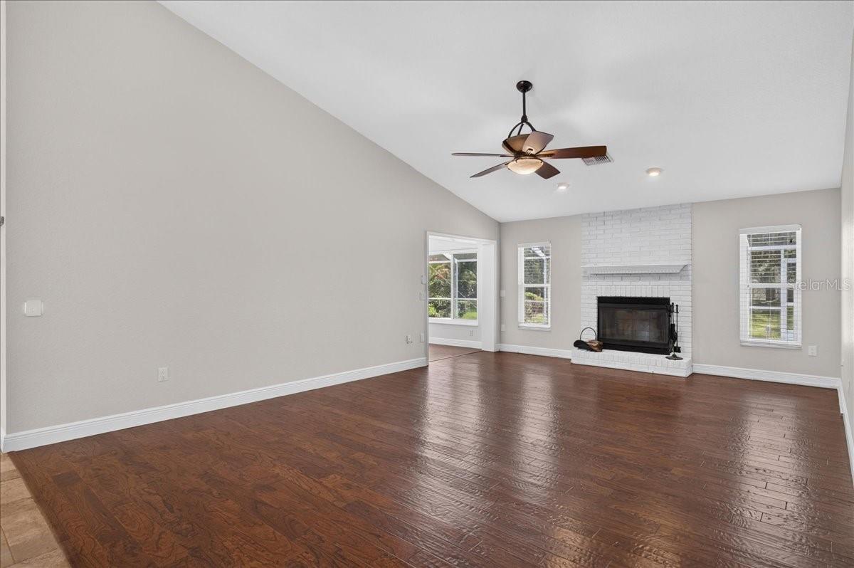 Vaulted ceilings and engineered hardwood floors enhance the main living area, where a whitewashed brick wood-burning fireplace and mantel add warmth and character.