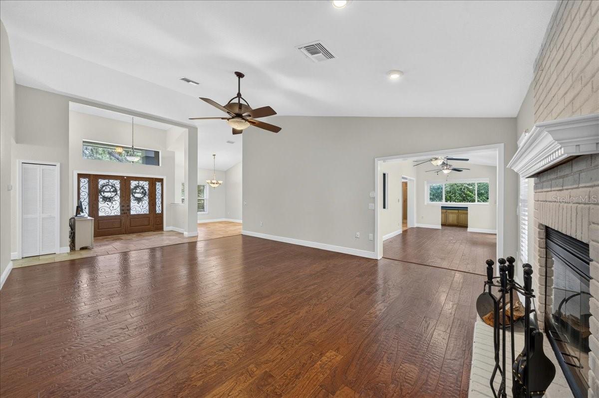Vaulted ceilings and engineered hardwood floors enhance the main living area, where a whitewashed brick wood-burning fireplace and mantel add warmth and character.