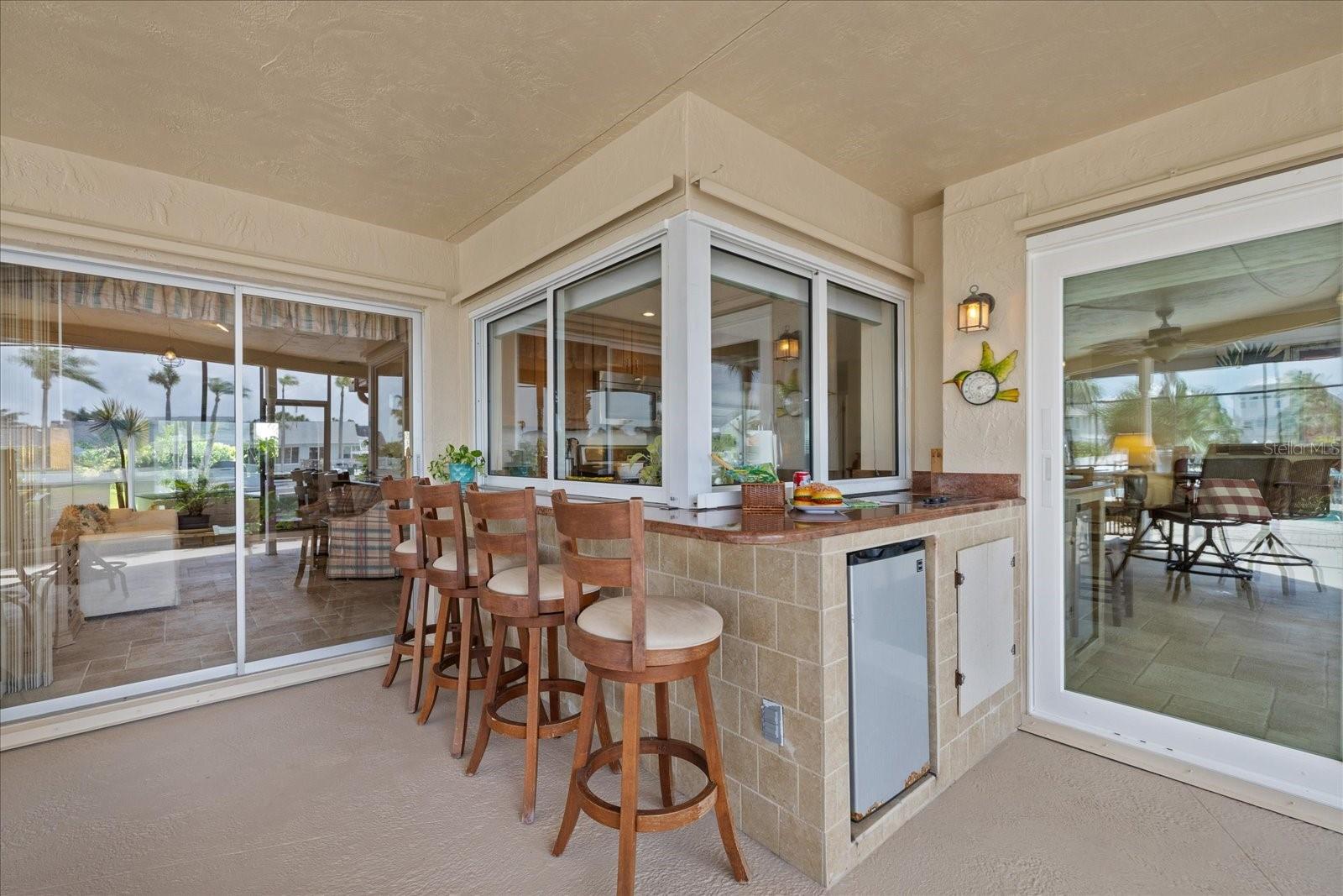 Pass through windows  to Outdoor electric jen-air cooktop, frig and bar area.