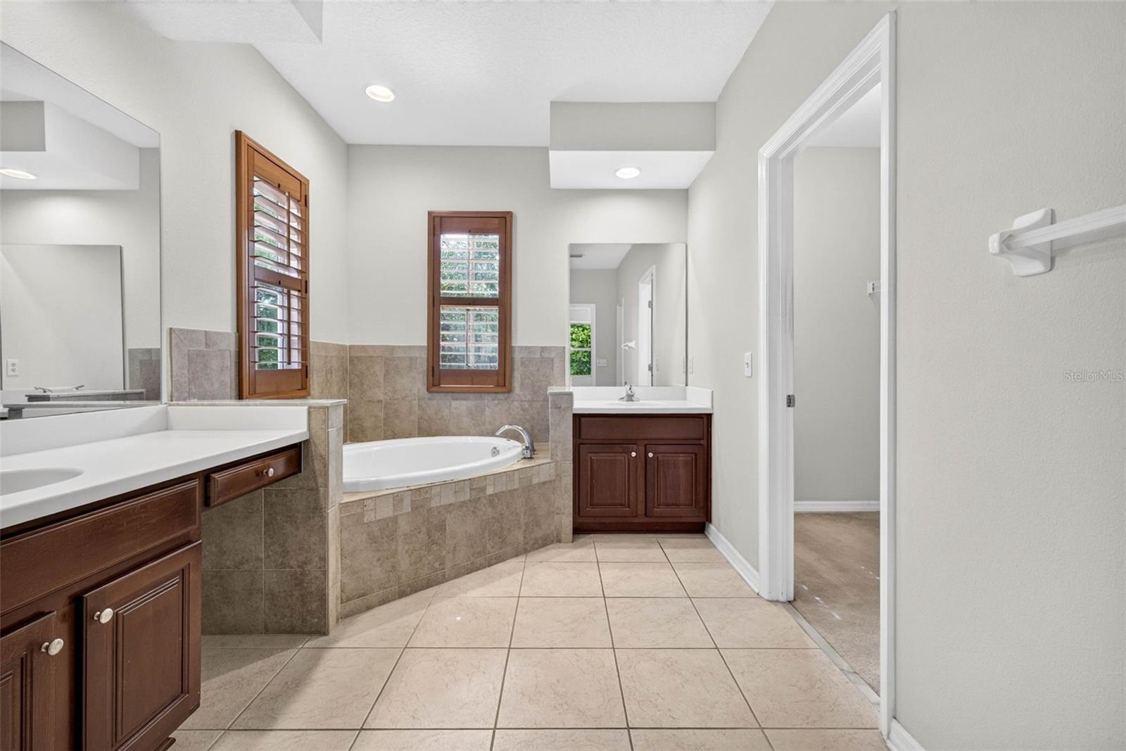 Primary bathroom with split vanities, soaking tub and plantation shutters