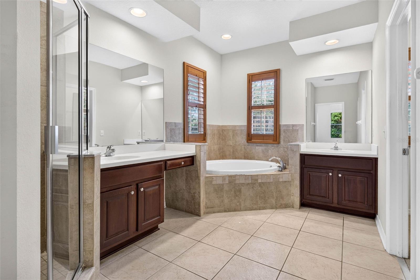 Primary bathroom with split vanities, soaking tub and plantation shutters