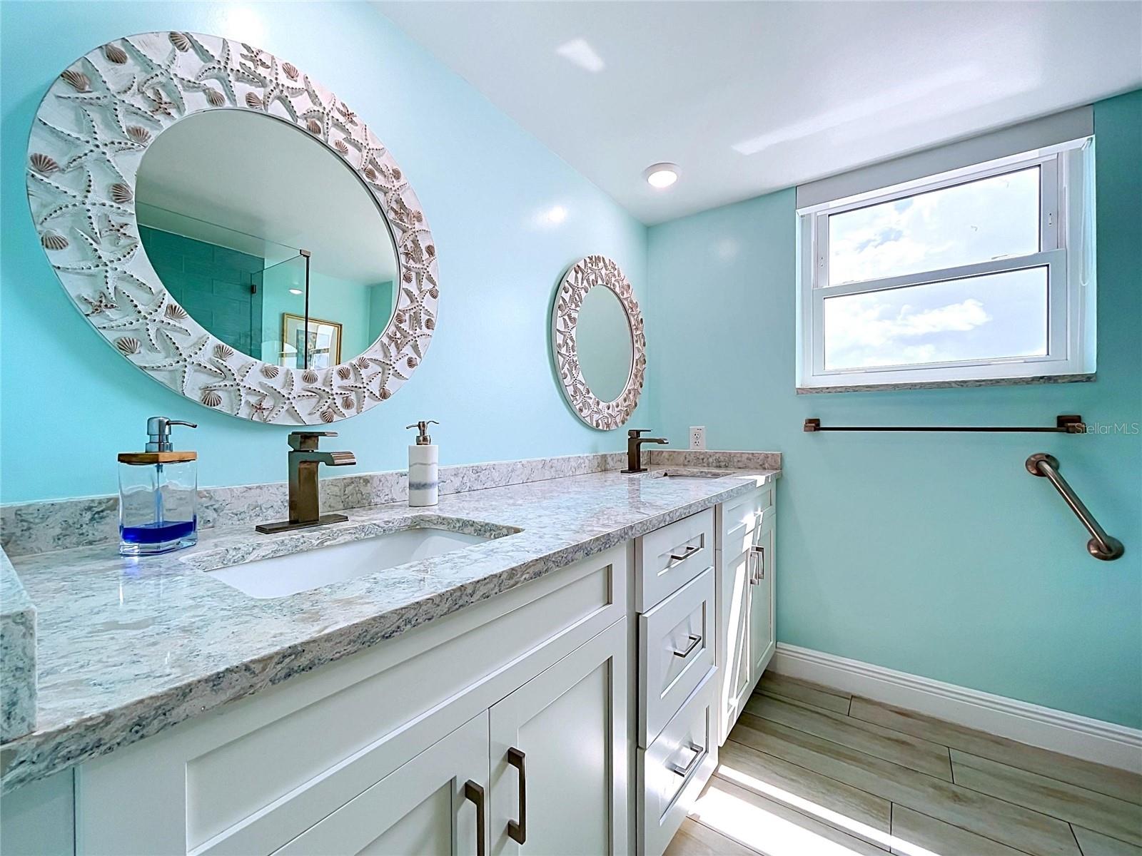The guest bathroom continues the beach theme and offers a walk-in shower, frameless glass and dual sinks.