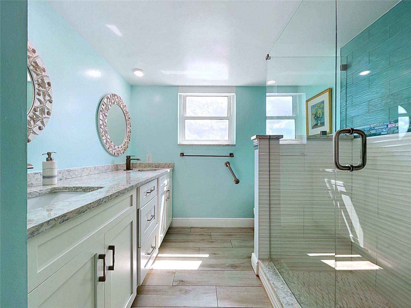 The guest bathroom continues the beach theme and offers a walk-in shower, frameless glass and dual sinks.