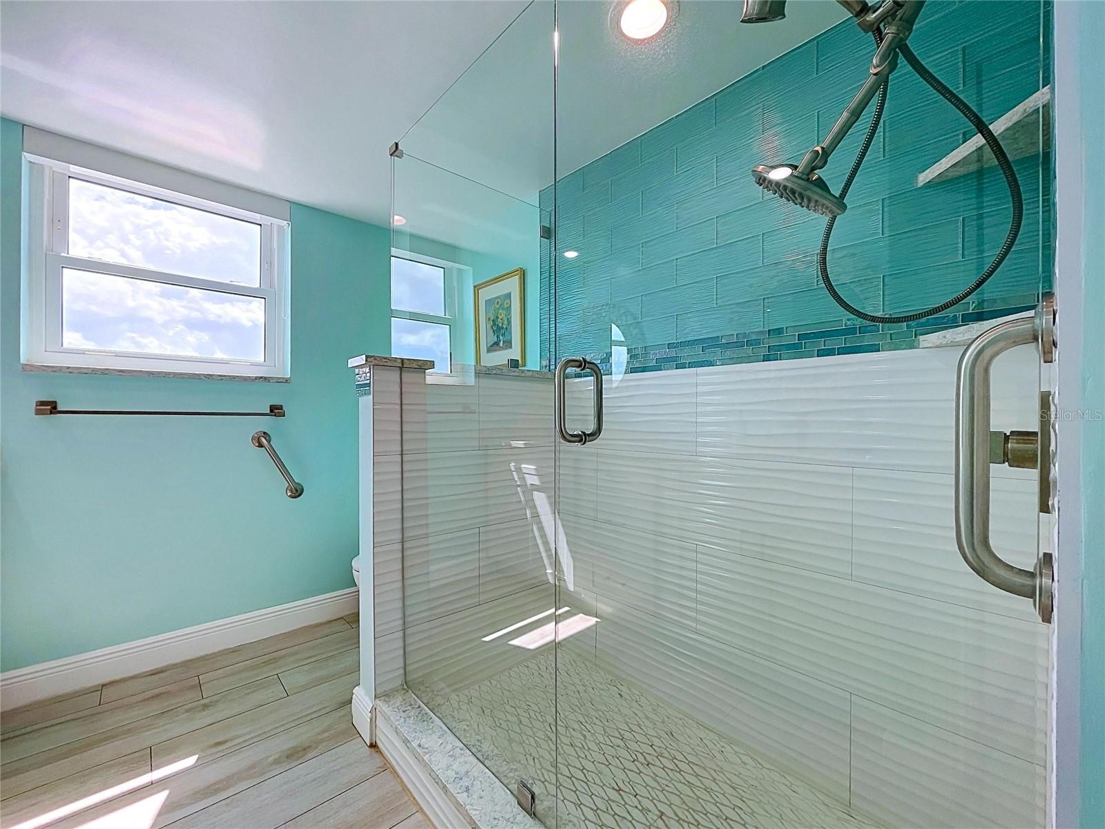 The guest bathroom continues the beach theme and offers a walk-in shower, frameless glass and dual sinks.