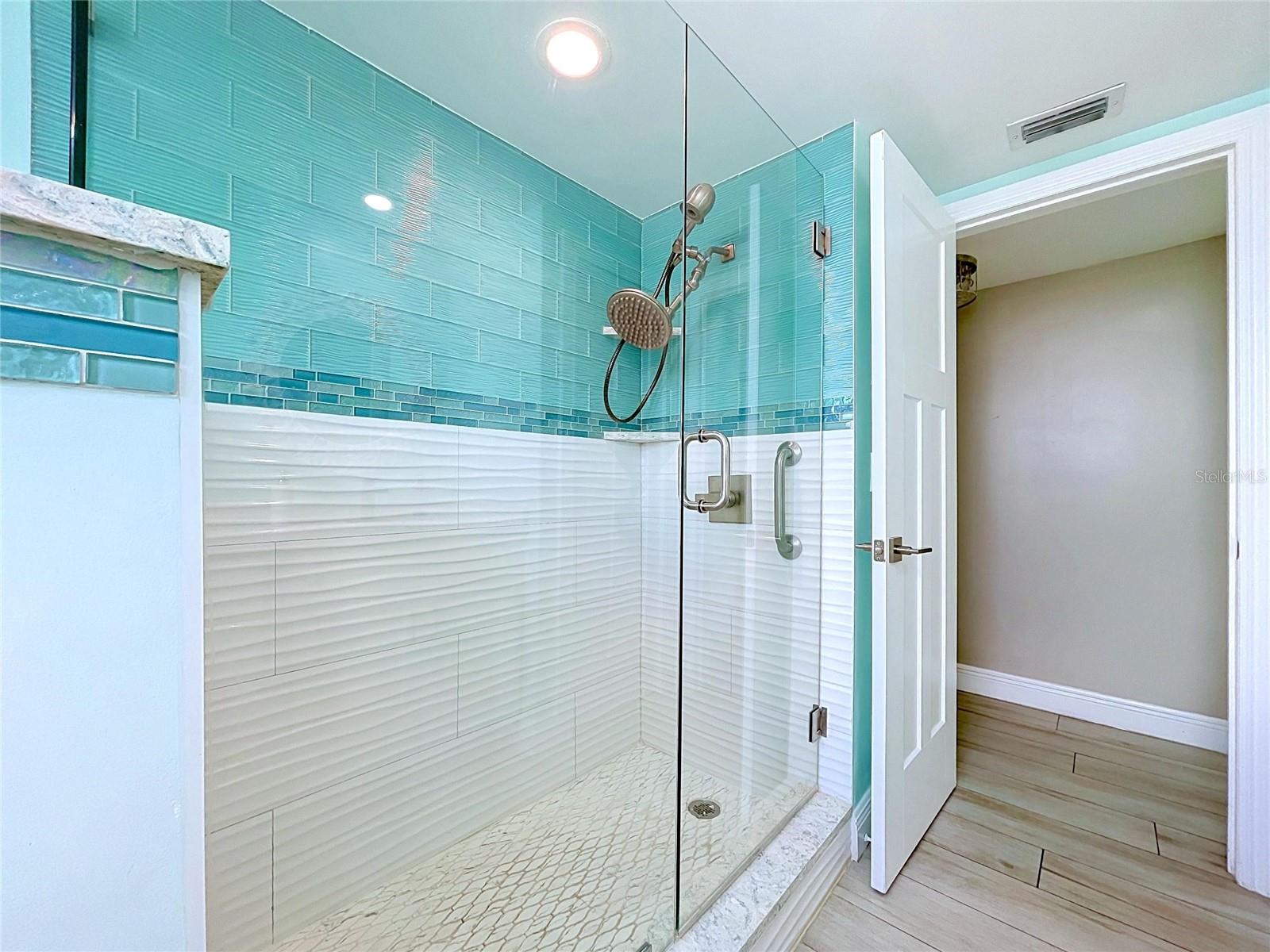 The guest bathroom continues the beach theme and offers a walk-in shower, frameless glass and dual sinks.