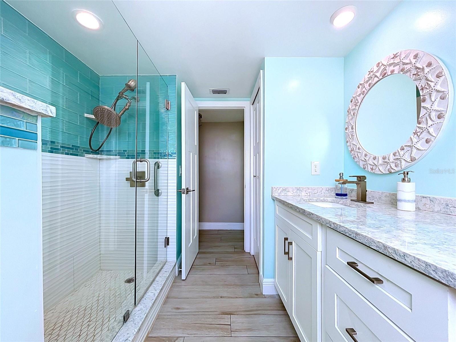 The guest bathroom continues the beach theme and offers a walk-in shower, frameless glass and dual sinks.