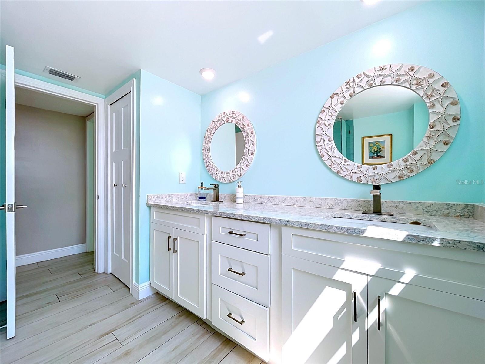 The guest bathroom continues the beach theme and offers a walk-in shower, frameless glass and dual sinks.