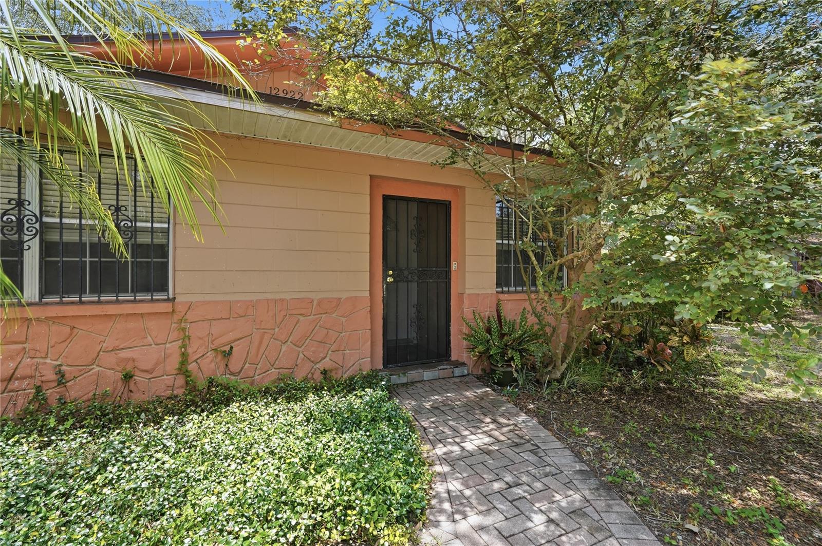 Shaded Pavered Walkway past Lush Landscaping to a Covered Screened Front Entry