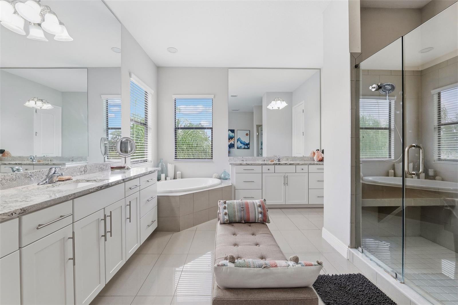 A Luxorious Primary Bathroom with Separate Vanities and Elegant Tub