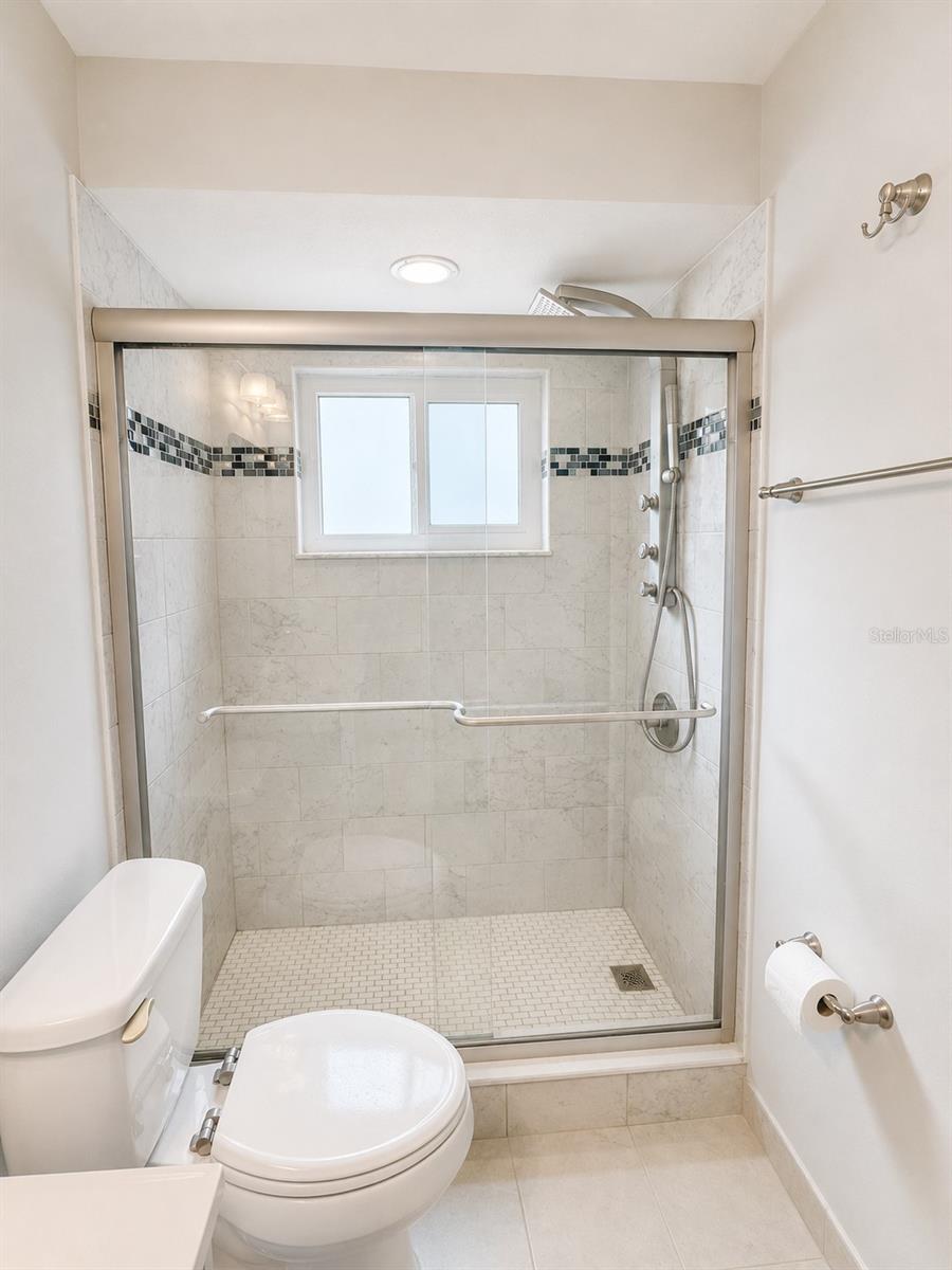 The primary bathroom features a lovely tiled shower with glass doors.