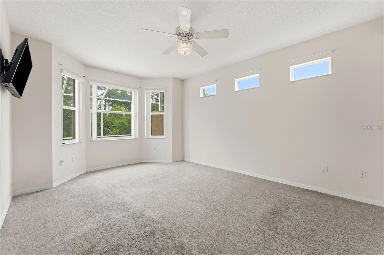 The first floor primary bedroom with a bay window and upper side windows providing nice natural light.