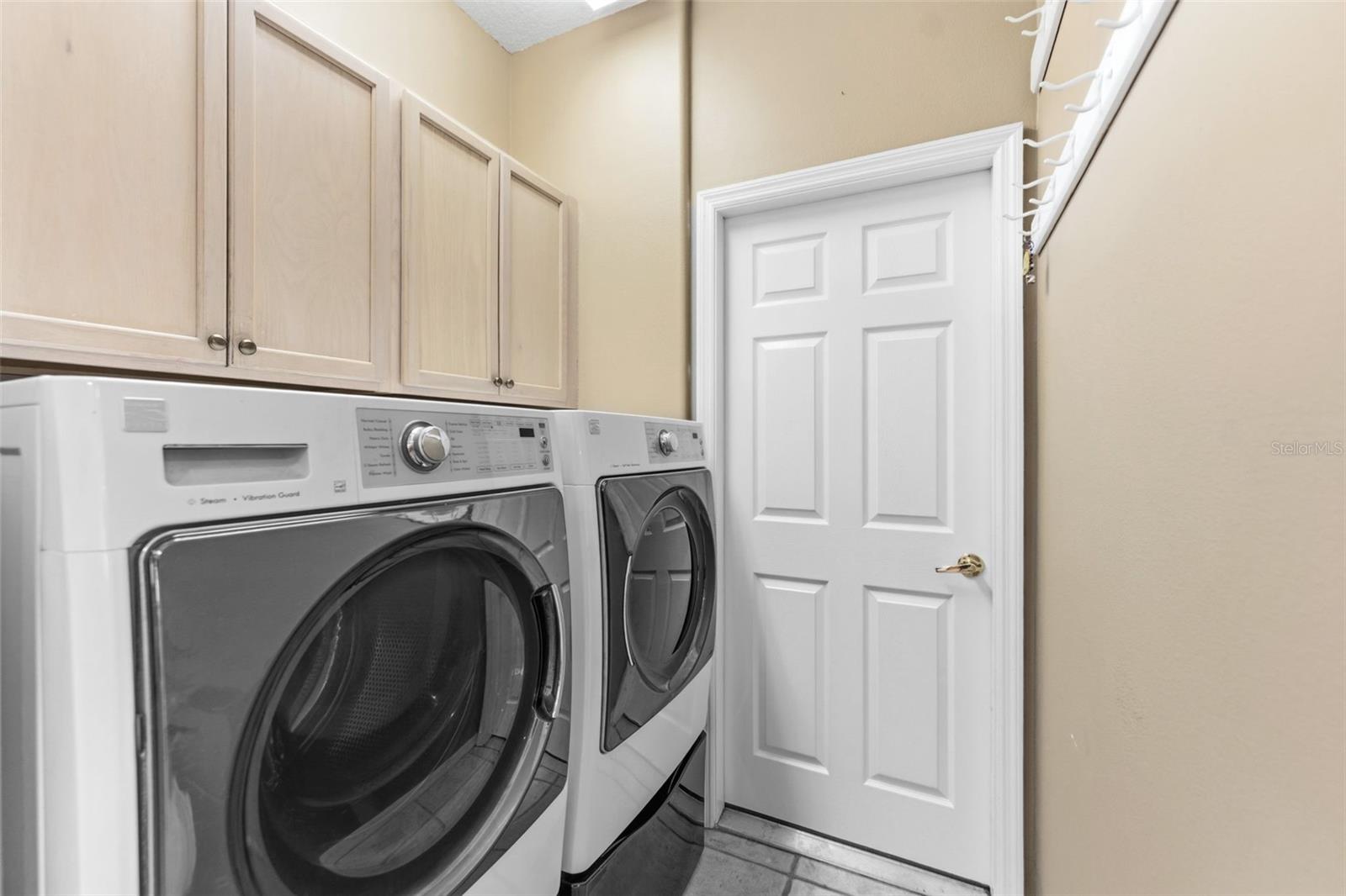 The indoor laundry room  with the newer washer and dryer, both with the under drawer for more storage.