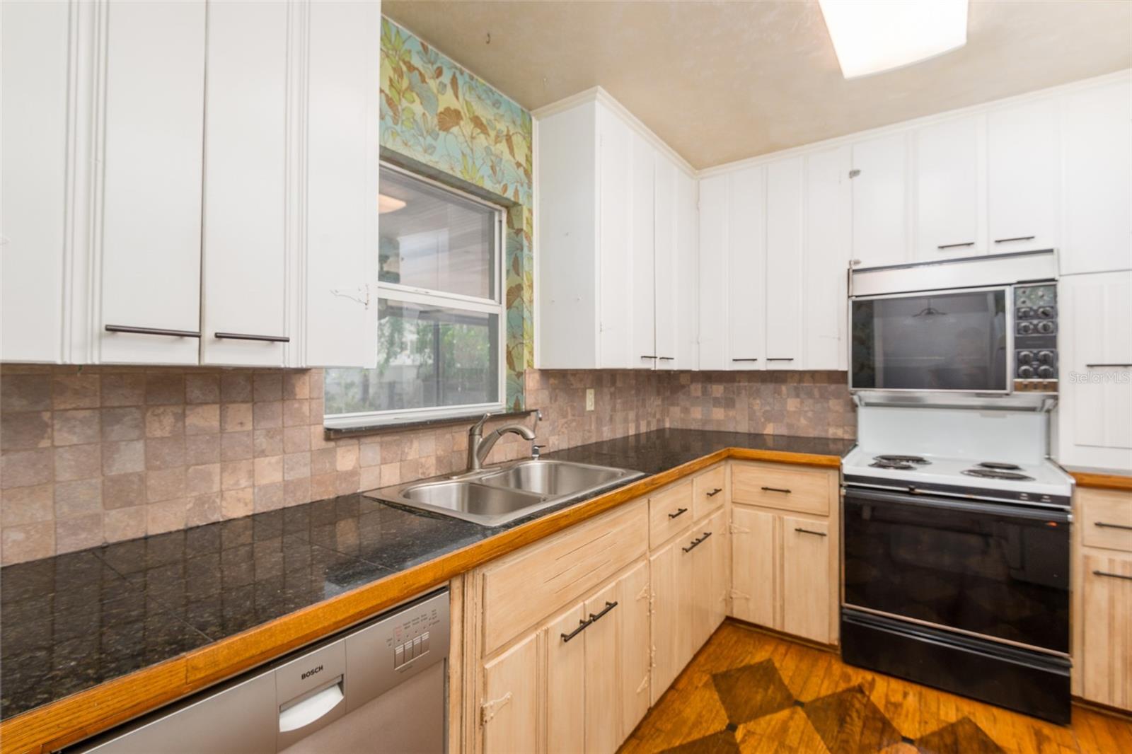 The kitchen has Bosch dishwasher; window looks out on lanai & backyard.