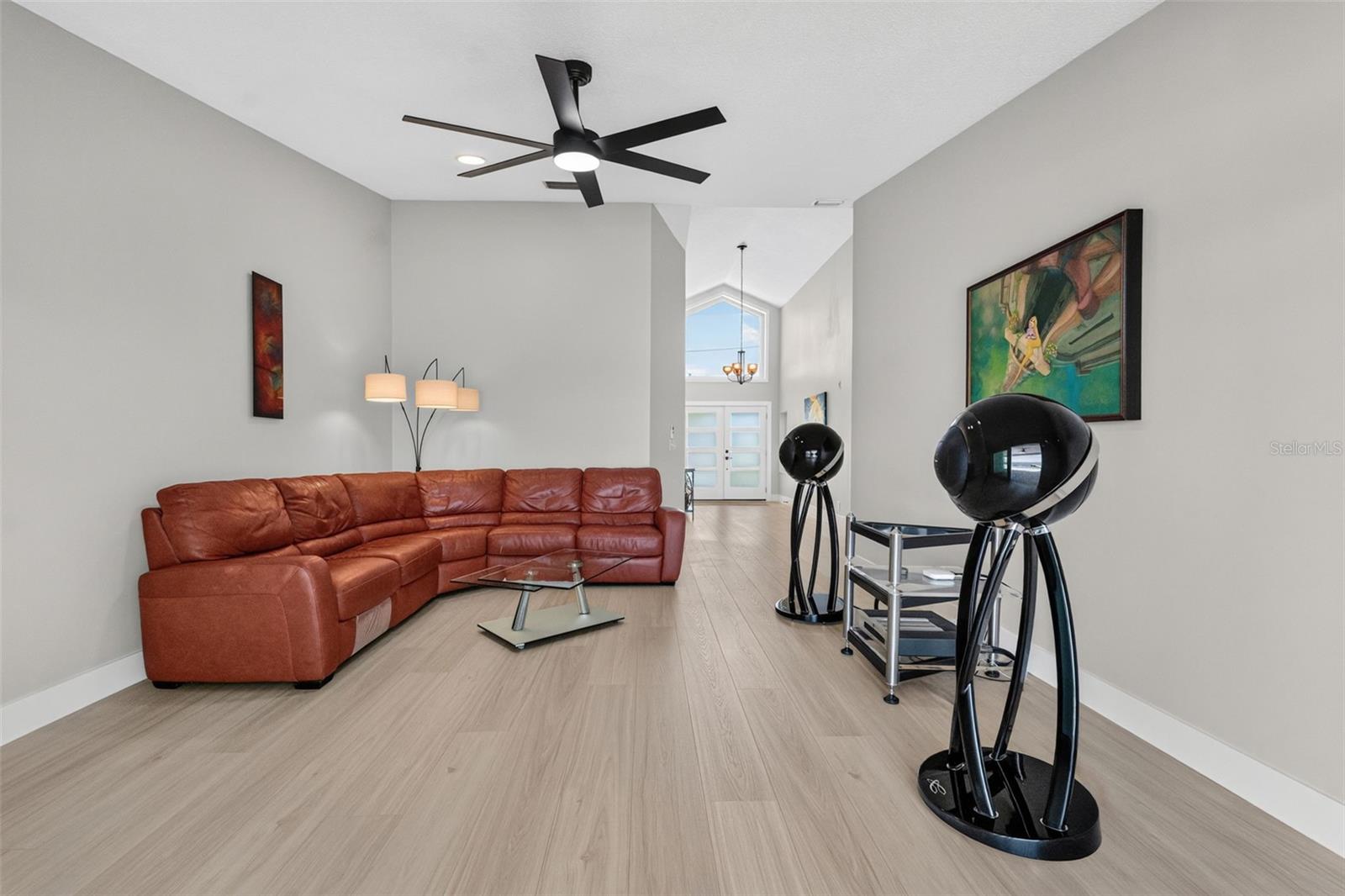 Formal living room with soaring vaulted ceilings and luxury vinyl plank flooring,  creating a grand and inviting space.