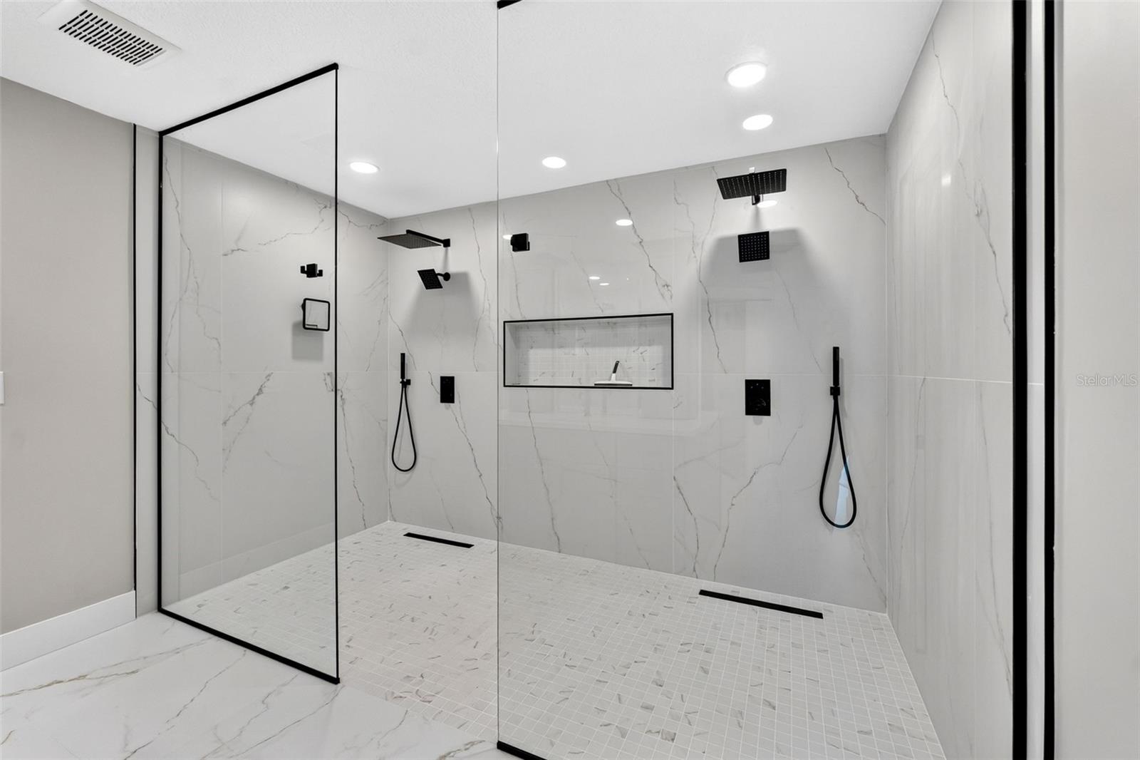 Oversized walk-in shower with seamless glass enclosure creating a spa-like experience
