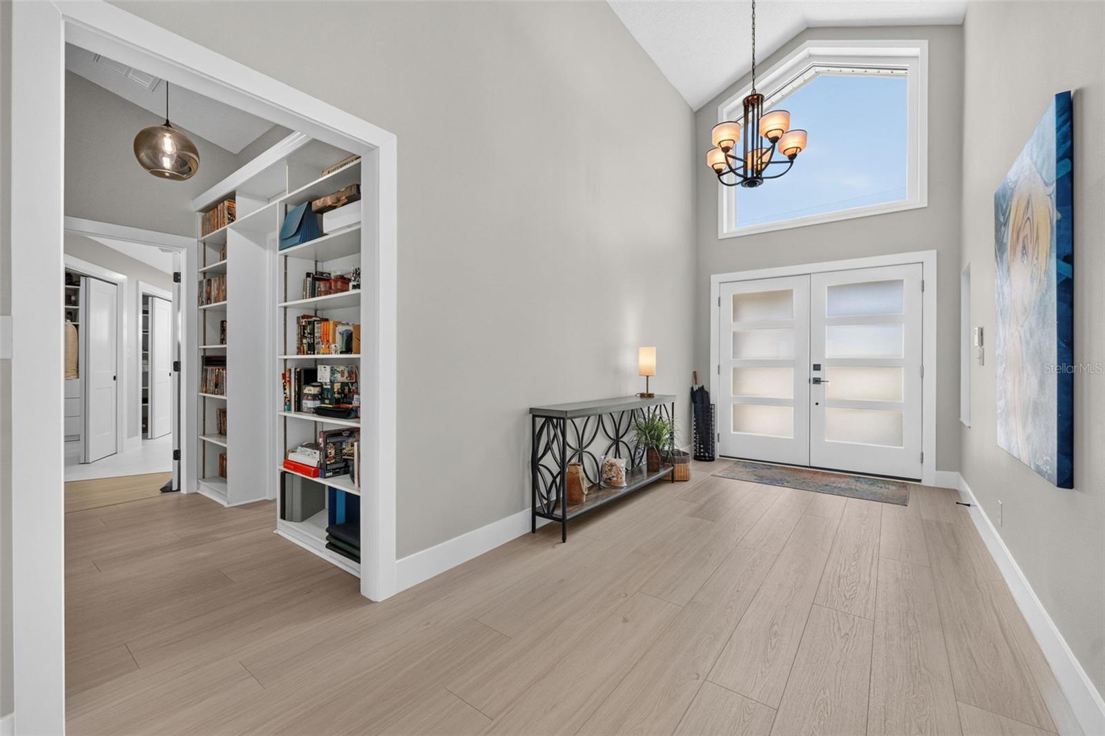 Bright and welcoming entryway featuring a large window above the double doors and a modern light fixture that enhances the natural light.