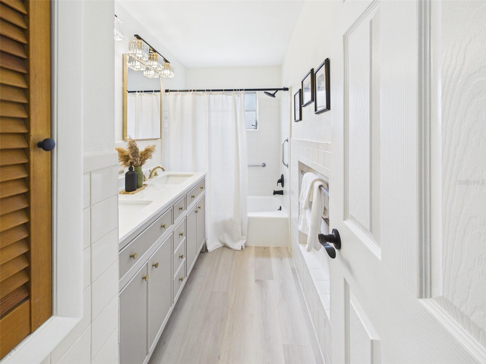 Primary bathroom with original tiles, brand new vanity, fixtures, and toilet, and refinished bathtub.