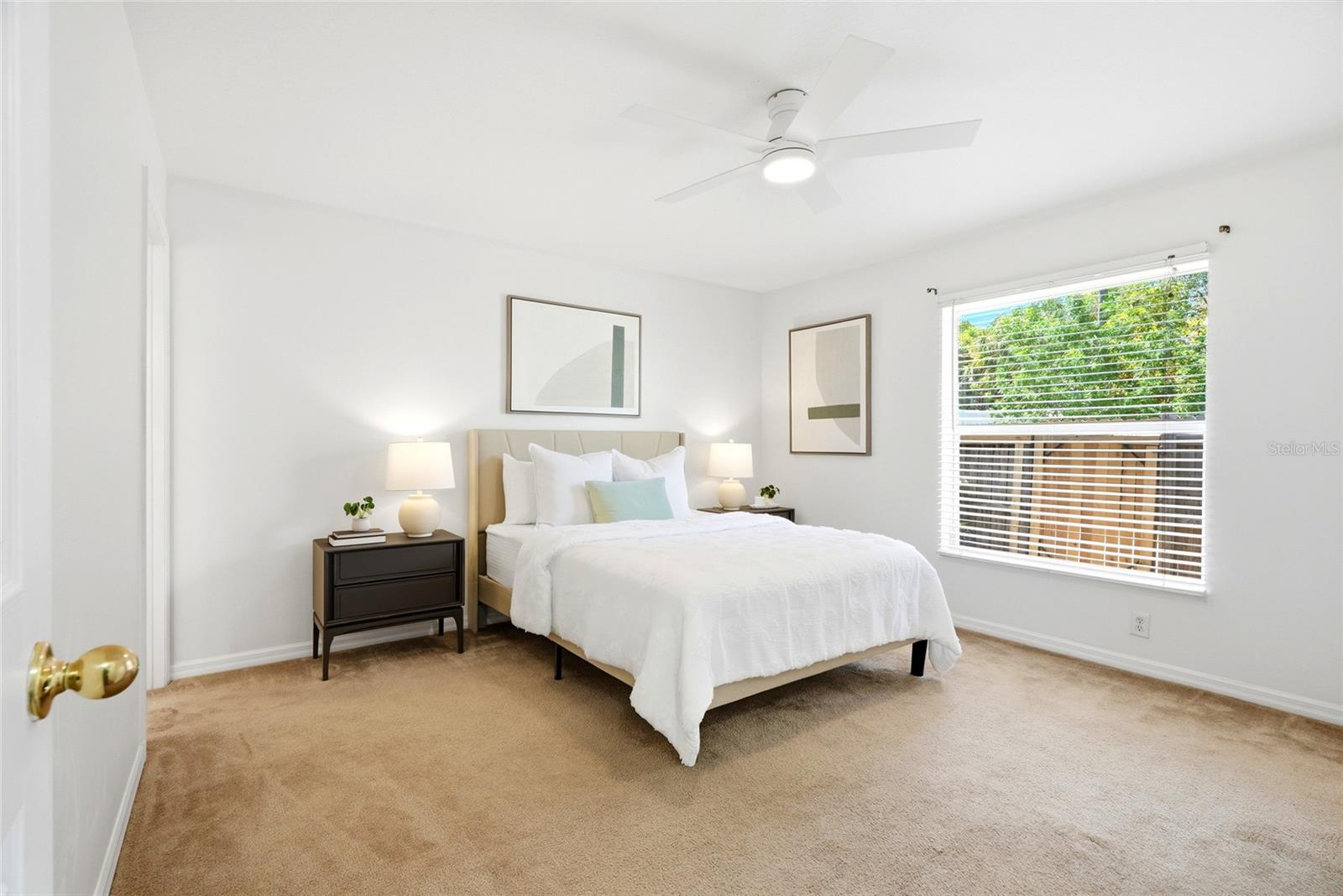 The generously sized primary suite offers a relaxing retreat, complete with a ceiling fan and soft natural light.