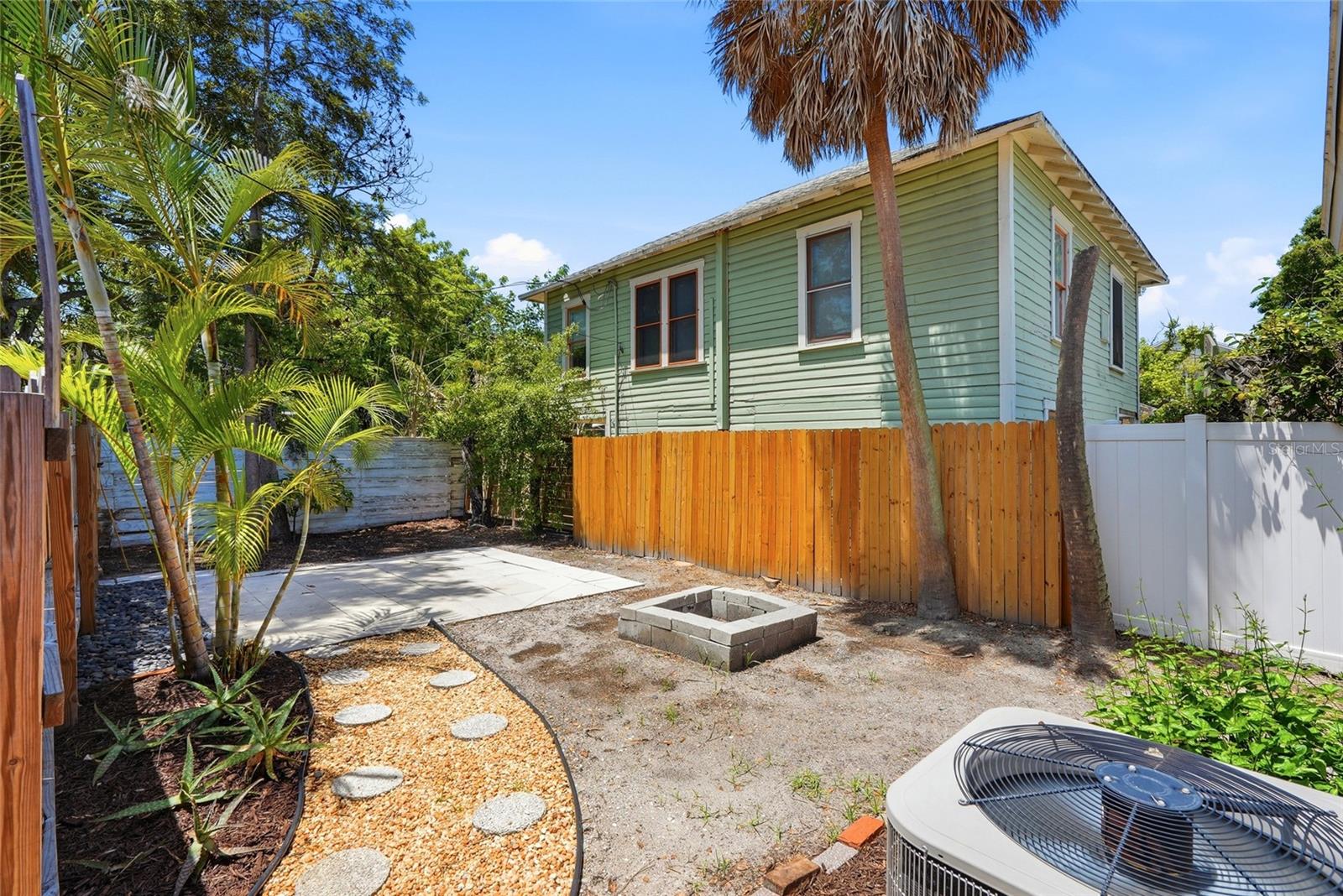 A private, fully fenced backyard with a patio area and built-in fire pit ready for evenings outdoors.