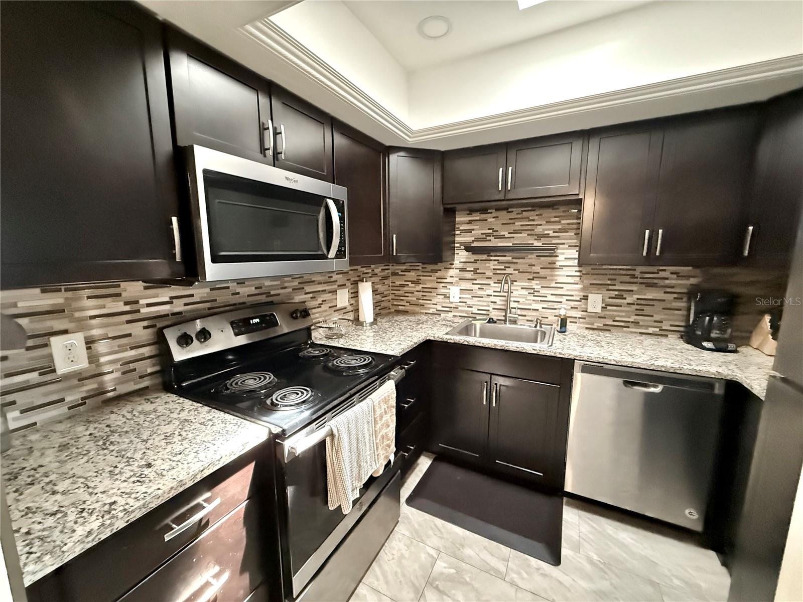 Designer kitchen w/ granite counters, stainless appliances, recessed lights n skylight
