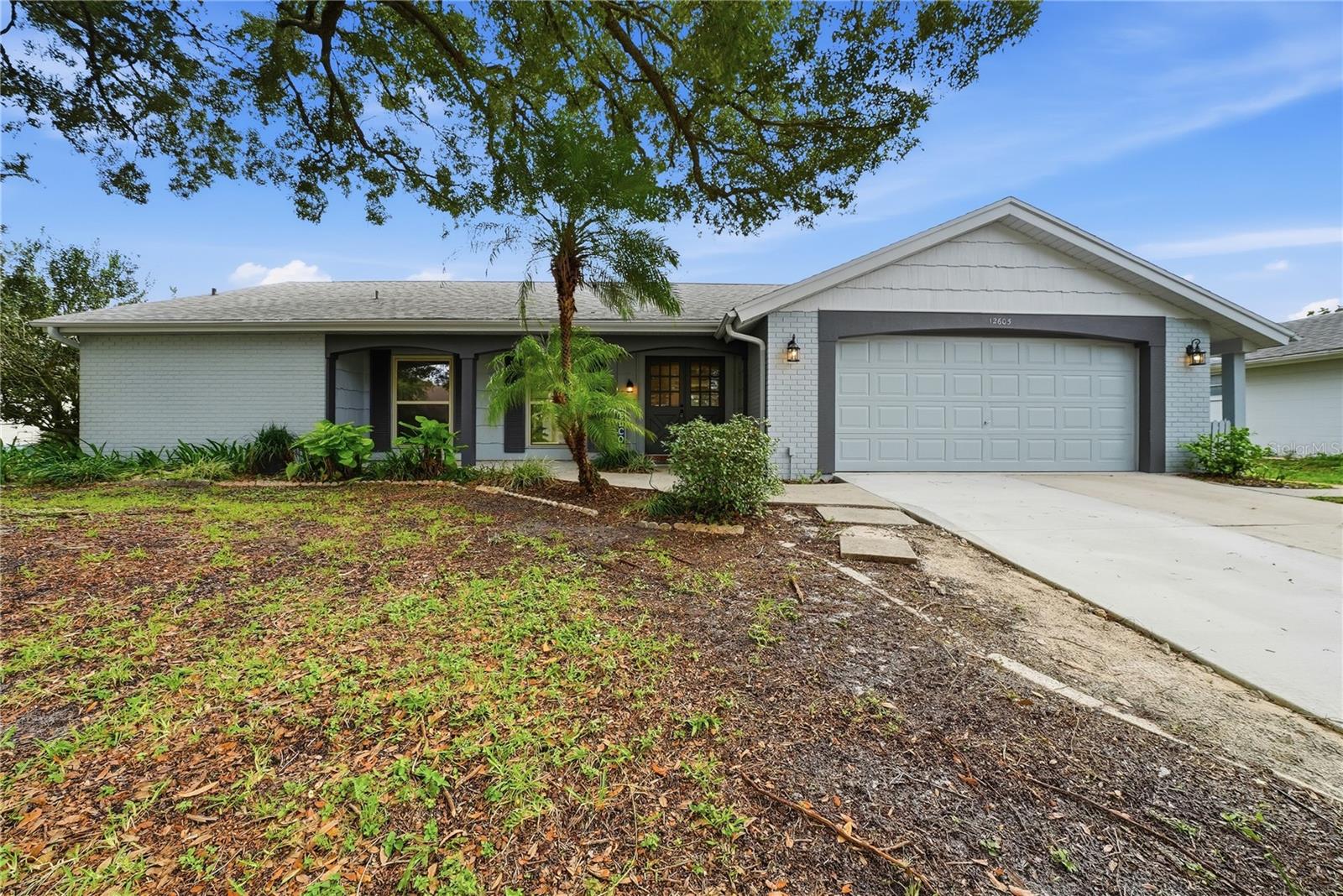 Freshly painted exterior with mature landscaping, an oversized two-car garage, and inviting covered entry.