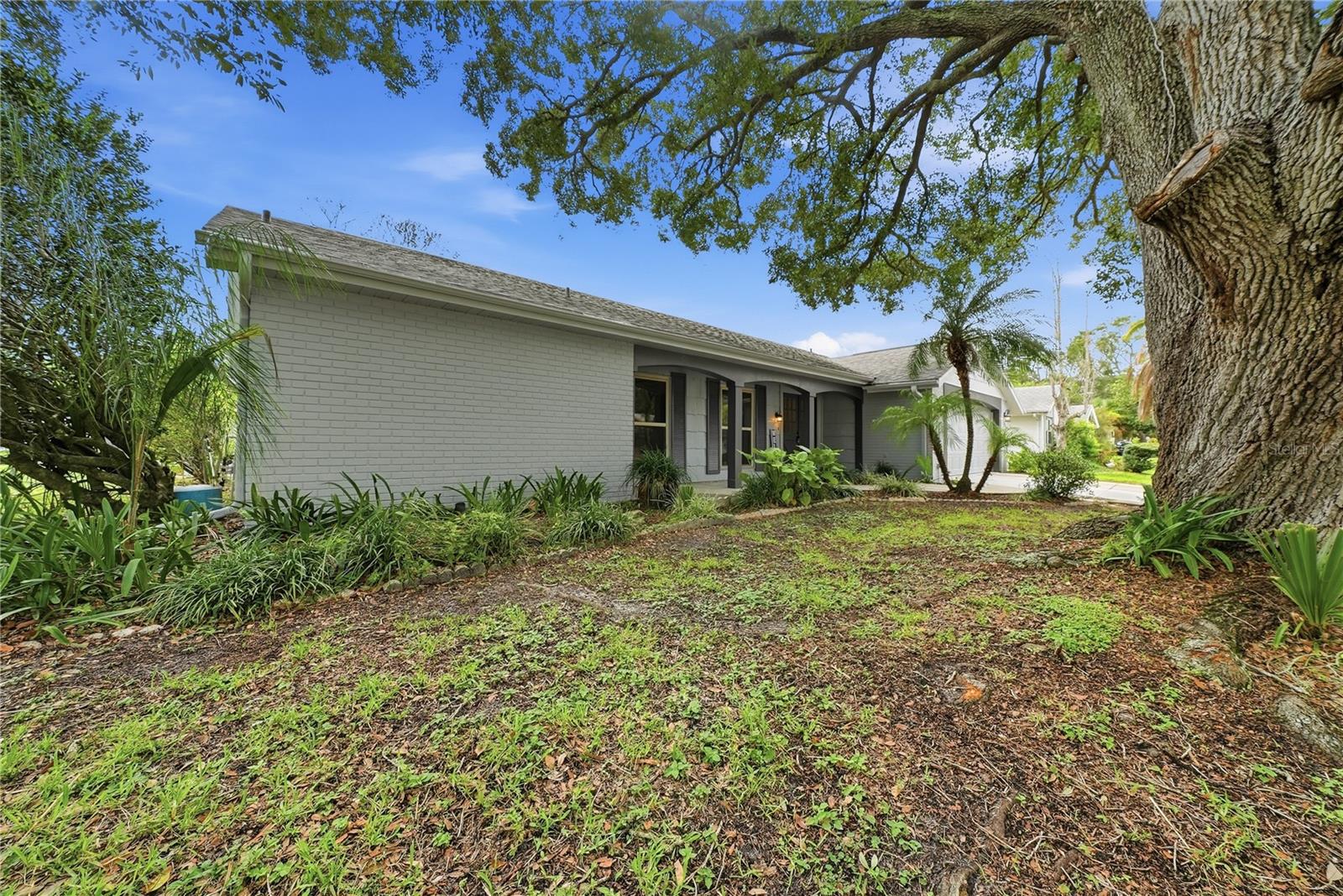 Attractive front elevation shaded by a beautiful mature oak tree and surrounded by established tropical landscaping.