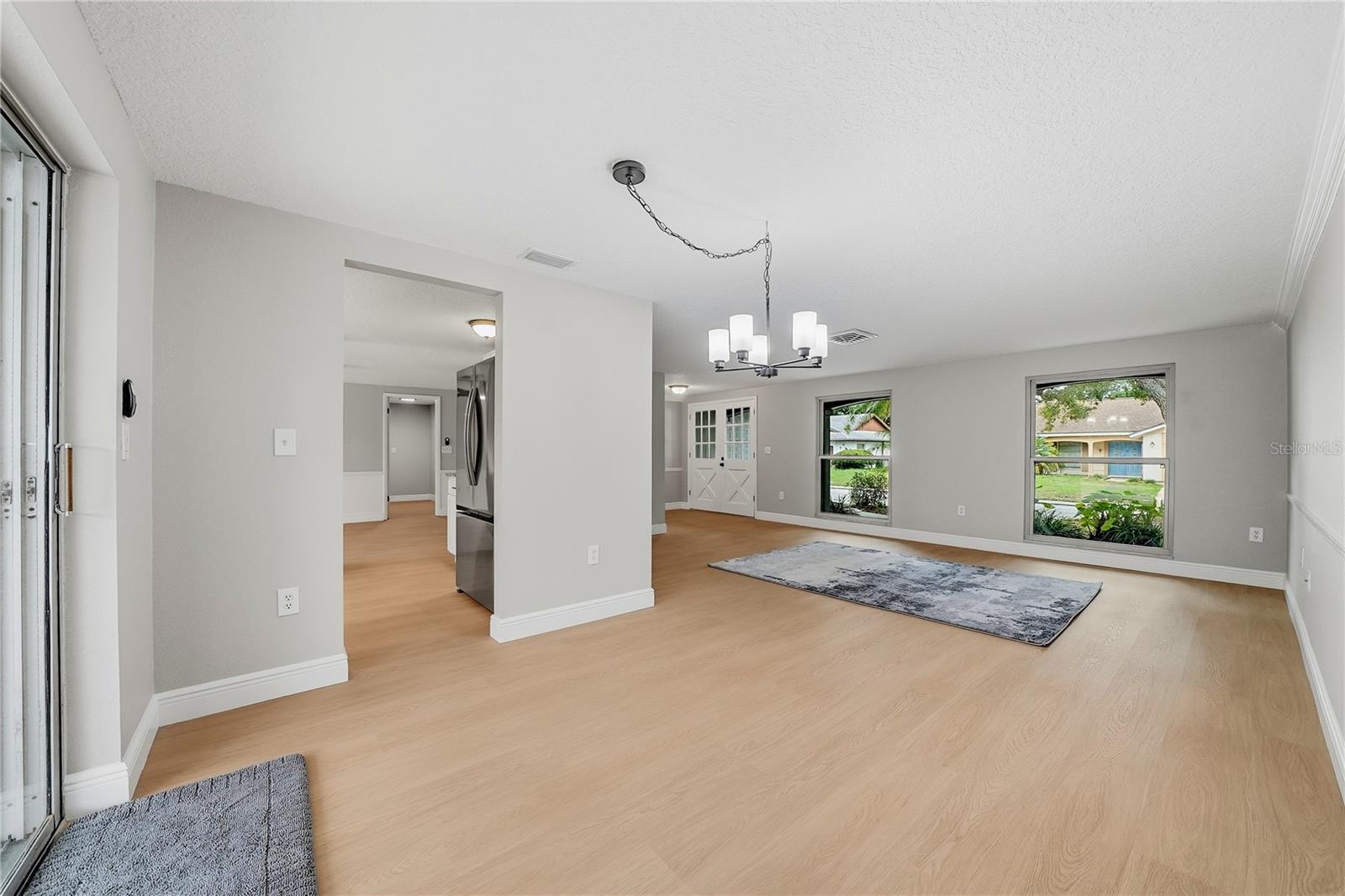 Light-filled living room showcasing the double-door entry, large front windows, and freshly updated interior.