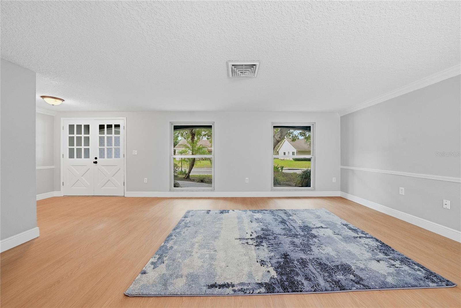 Versatile family or dining room with decorative wall paneling, modern ceiling fan, and sliding doors to the pool.