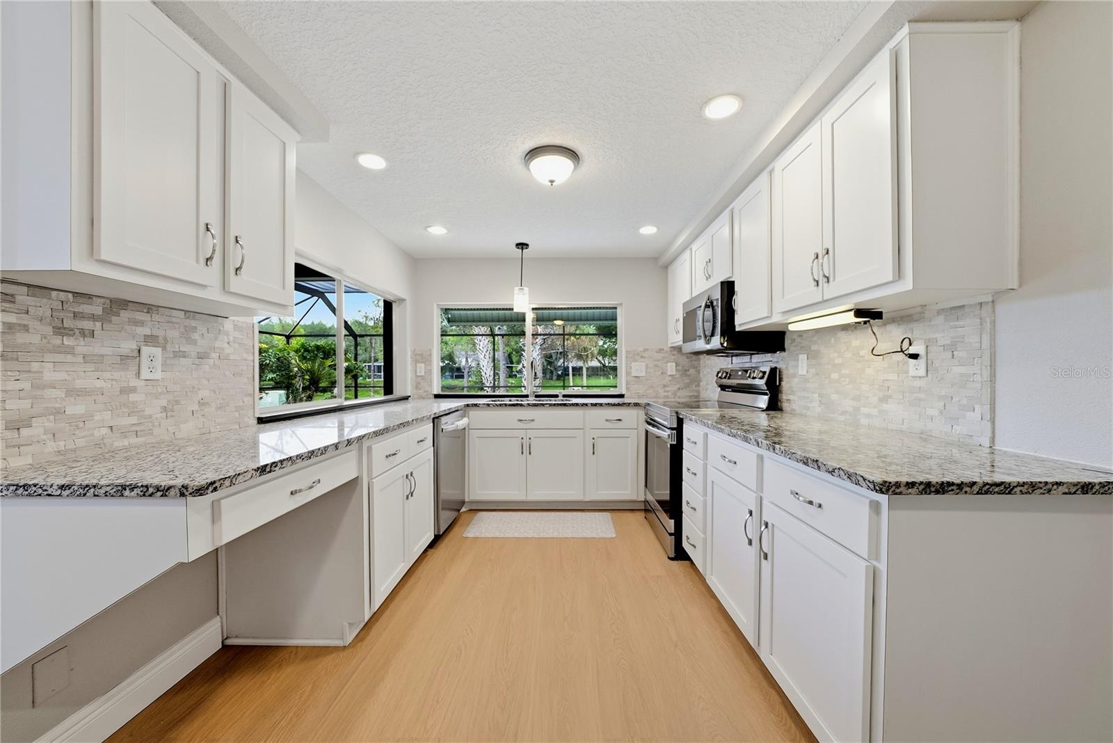 Remodeled kitchen with white cabinetry, granite countertops, stainless-steel appliances, and abundant workspace.