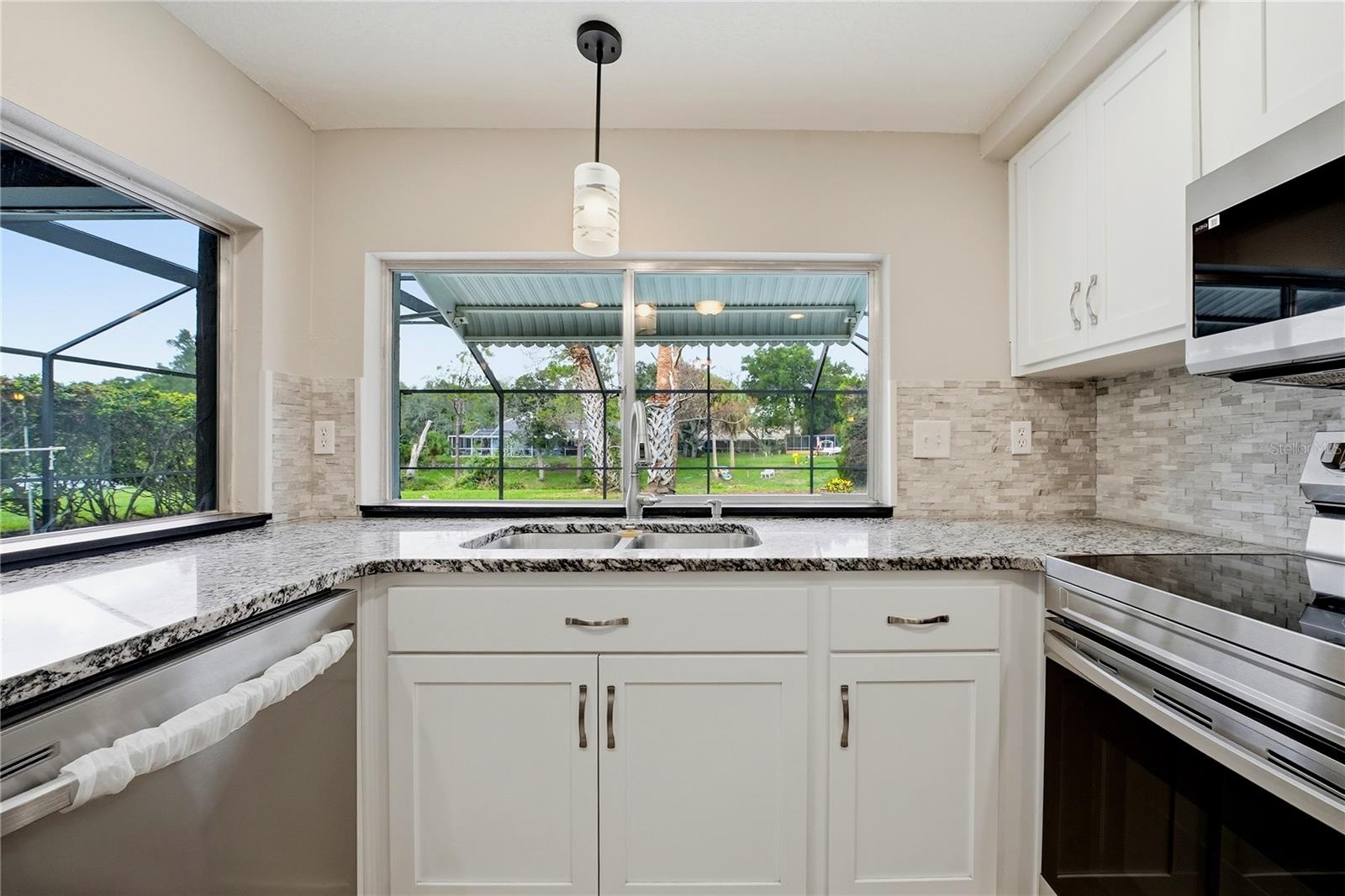 Kitchen sink overlooks the screened pool and backyard through oversized corner windows.
