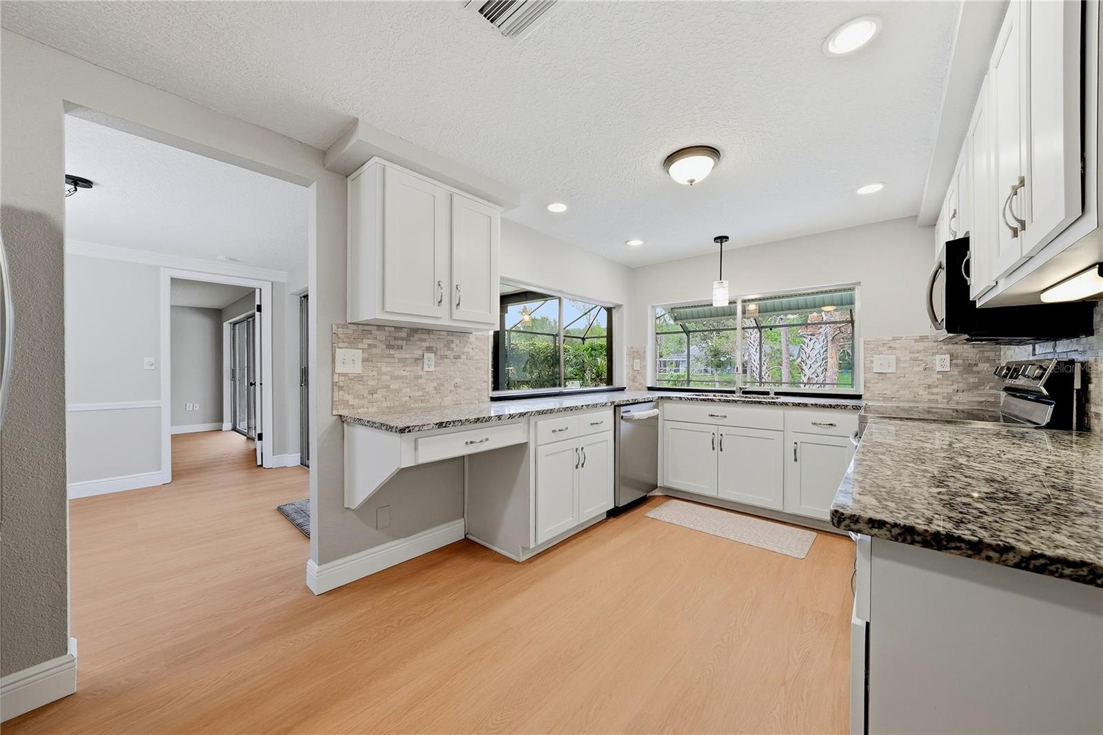 Bright remodeled kitchen with extensive counter space, recessed lighting, and peaceful views of the outdoor living area.