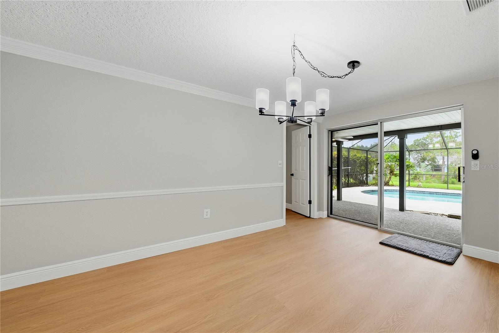 Dining area with modern lighting and sliding glass doors opening directly to the screened pool.