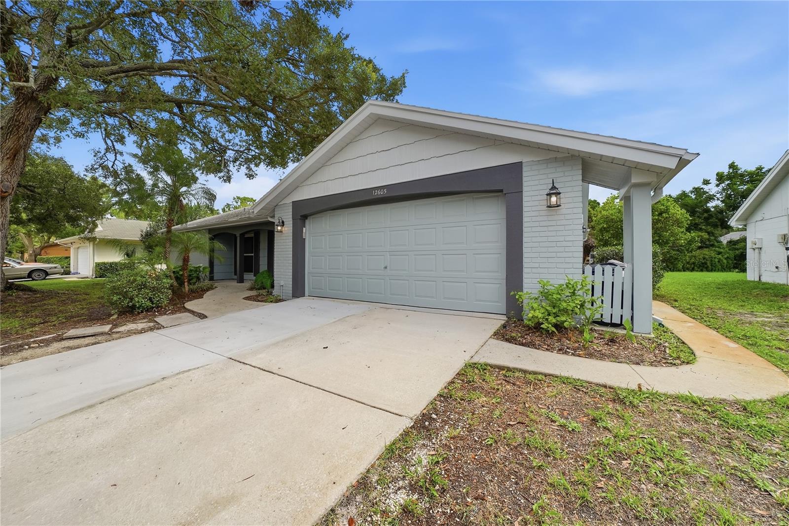 Spacious driveway and attached two-car garage with updated exterior lighting and fresh paint.