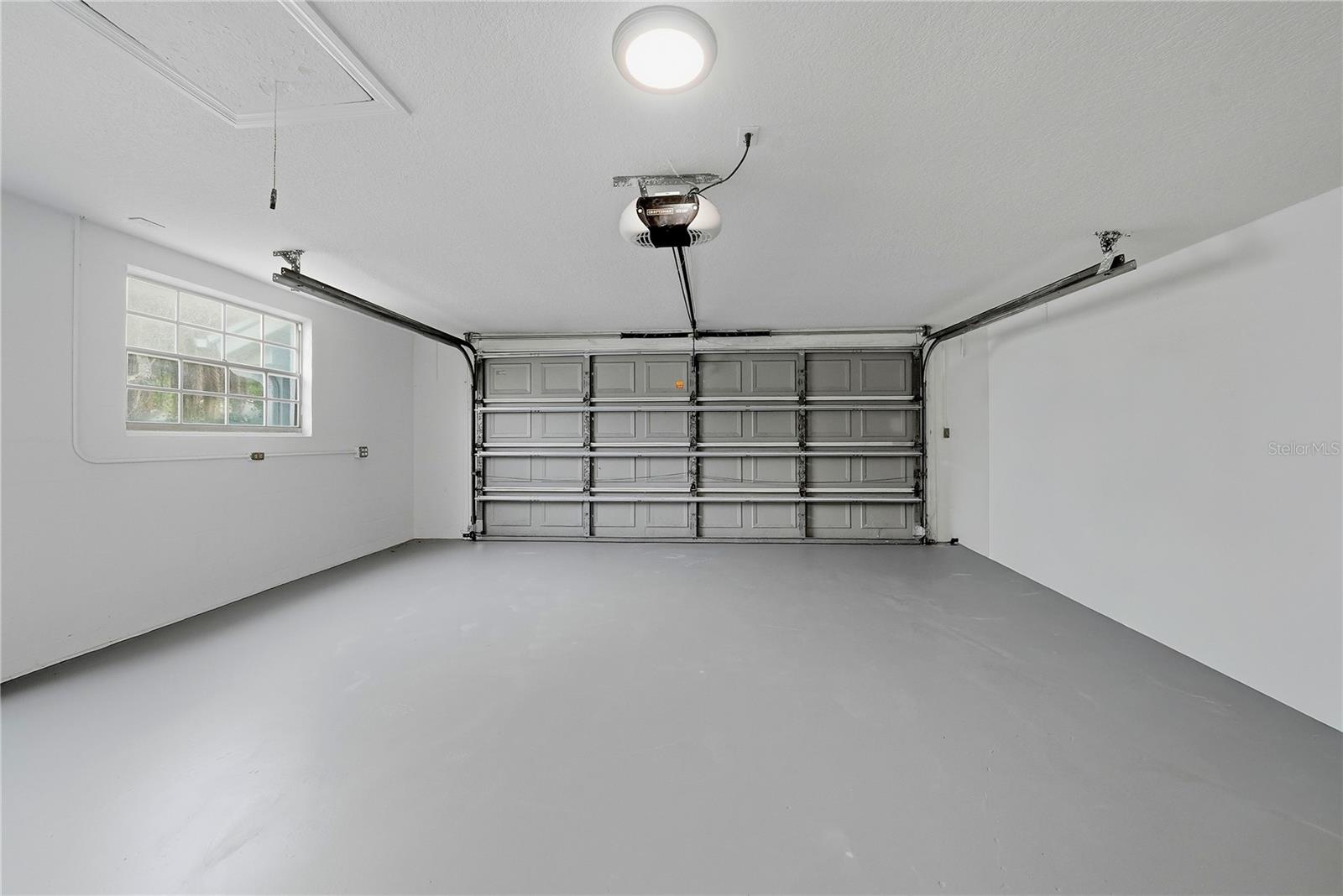 Clean and spacious two-car garage with freshly finished floor, natural light, and automatic garage-door opener.