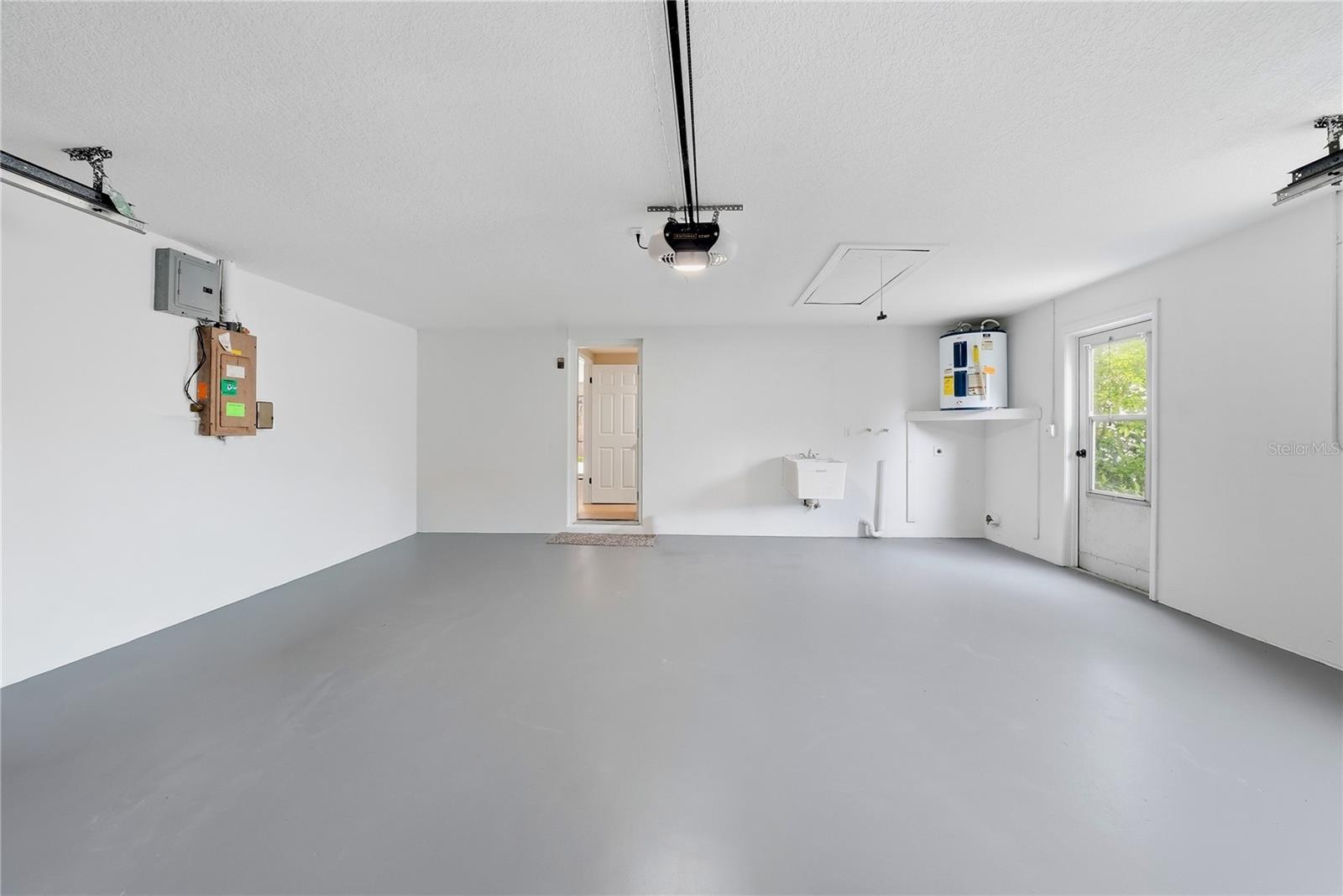 Oversized garage offering, utility sink, water heater, attic access, and additional storage potential.