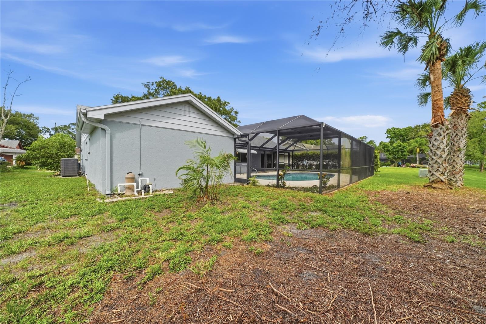 Rear exterior view featuring the expansive screened pool enclosure and open backyard setting.
