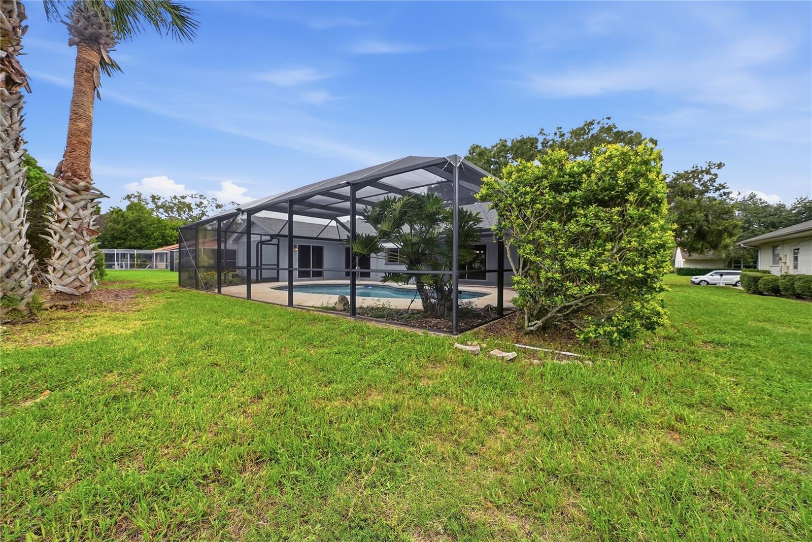 Spacious backyard with tropical landscaping and a large screened enclosure surrounding the private pool.