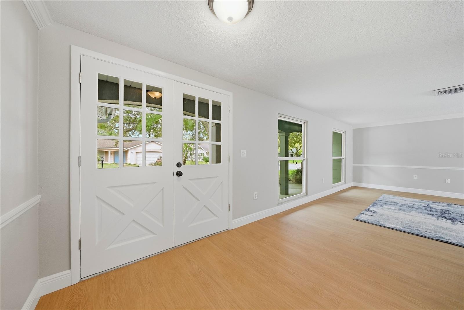 Bright interior entry with distinctive double doors, new flooring, fresh neutral paint, and crisp white trim.
