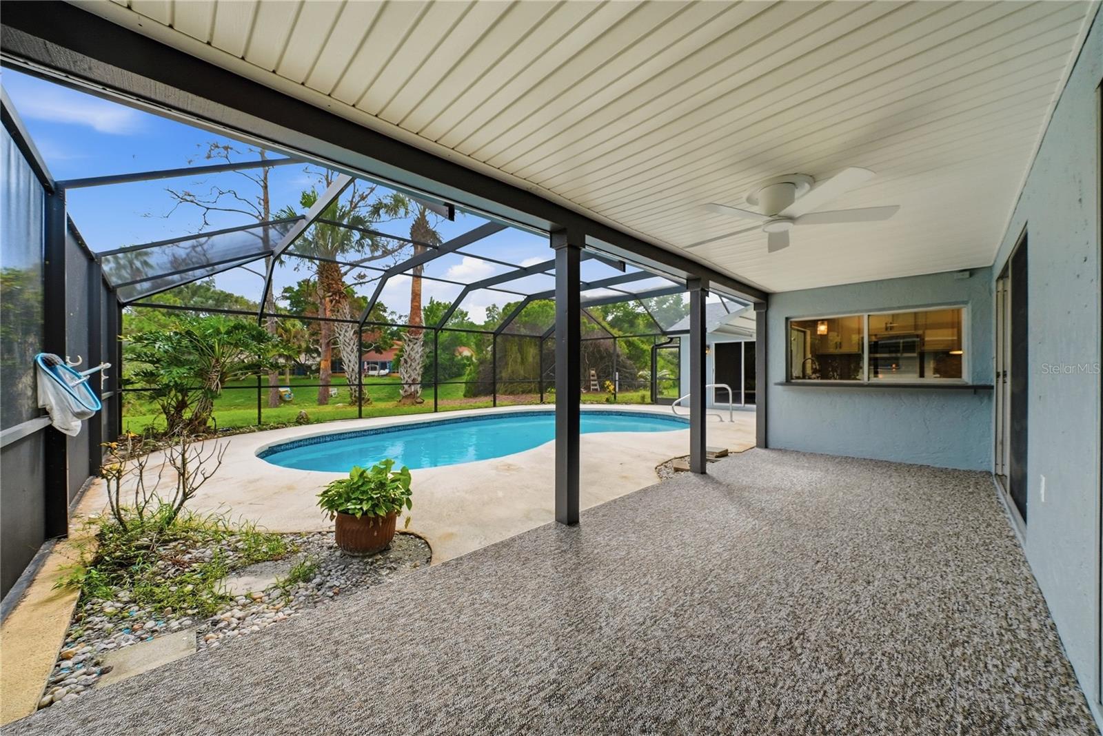 Large covered outdoor living space overlooking the screened pool—ideal for relaxing or entertaining.