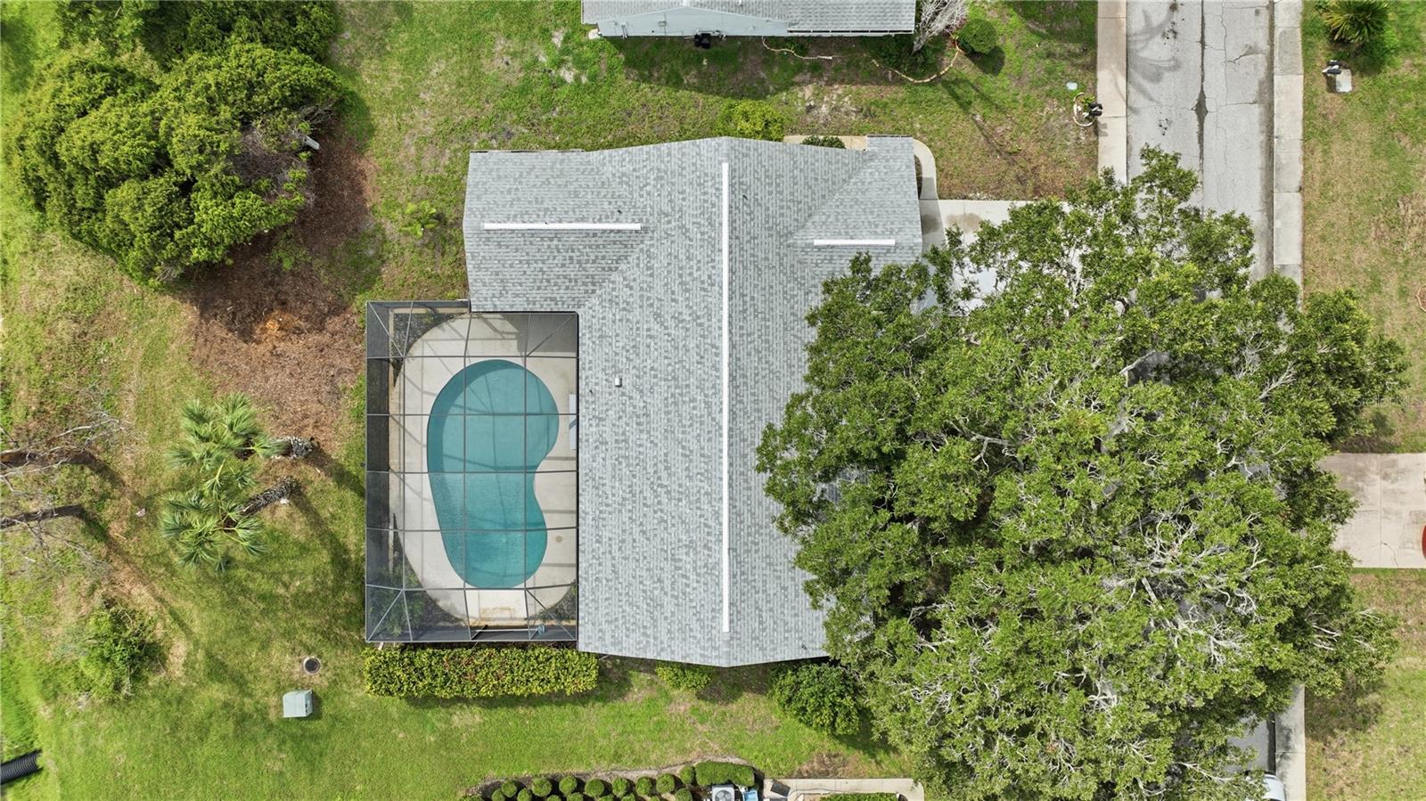 Overhead aerial view highlighting the home’s expansive roofline, screened pool enclosure, and generously sized lot.