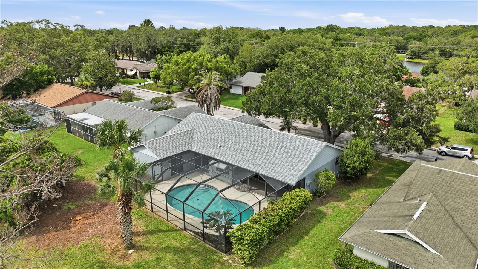 Elevated rear aerial showcasing the private screened pool, mature landscaping, and established neighborhood setting.