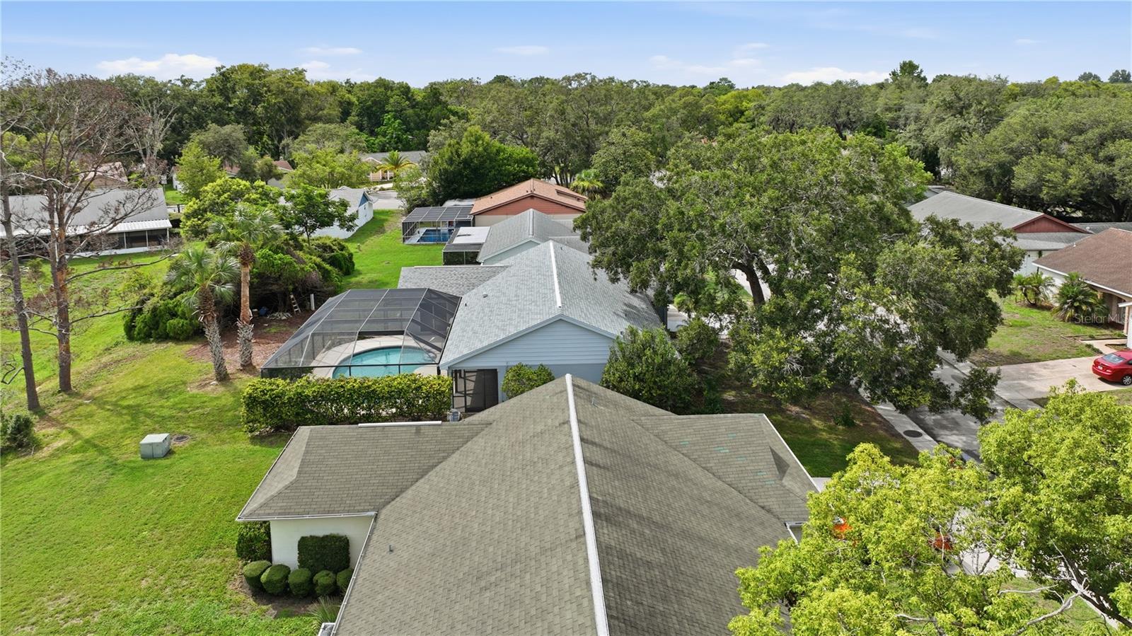 Aerial perspective of the home and surrounding community with abundant greenery and spacious outdoor areas.